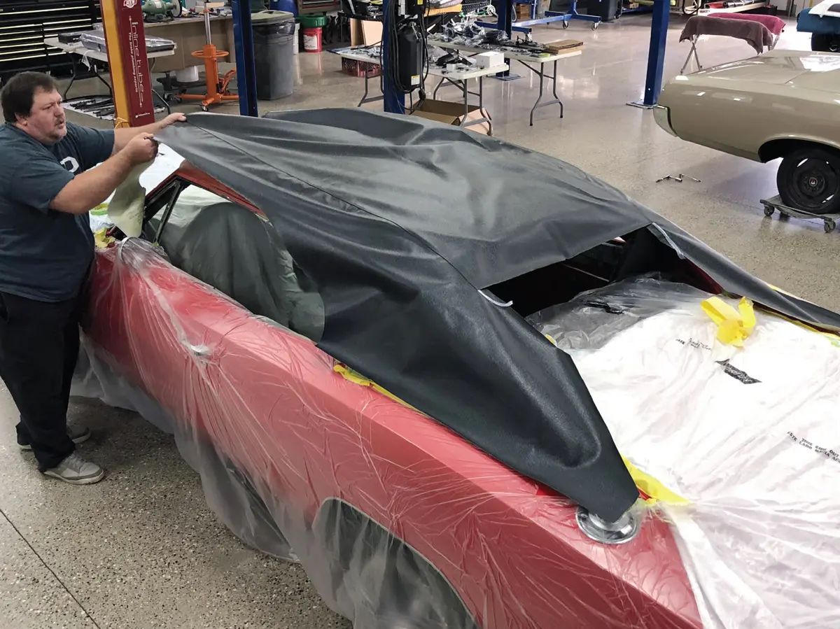 high angle view of a mechanic Bob Stedman in the process of applying a vinyl roof to a red '69 charger