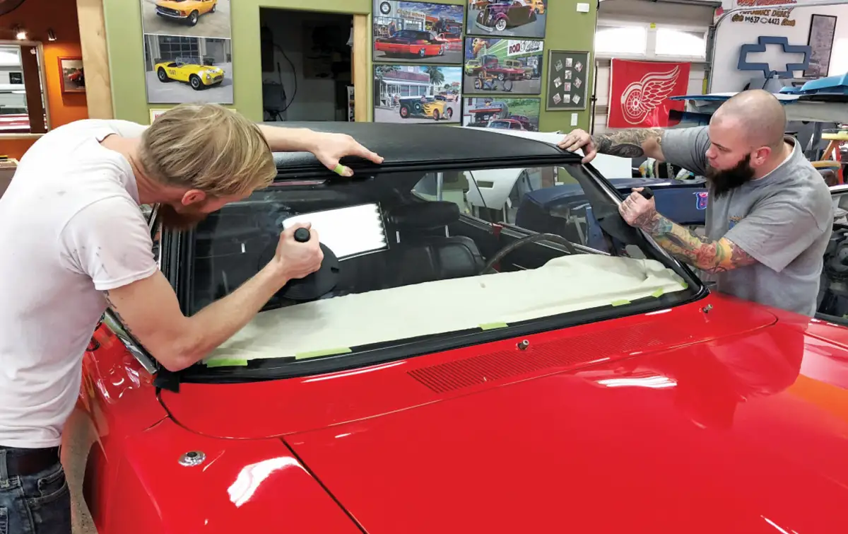 angled view of two mechanics reinstalling the windshield