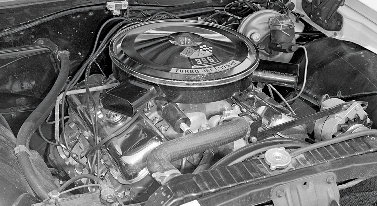 Black and white close-up landscape photograph view of a 1964 Chevy Malibu car internal engine parts mainly showcasing the turbo-jet 396-/375 HP engine located in the middle