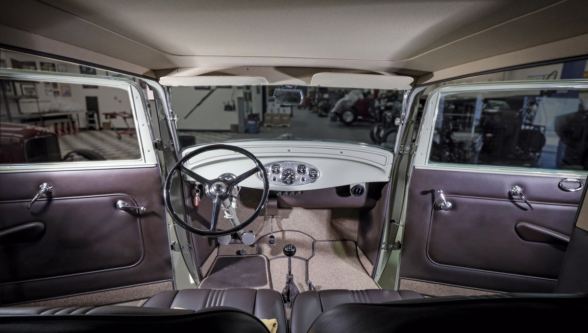 view of front seats, dashboard, and gearshift inside ’32 Ford Sedan Delivery with front doors open