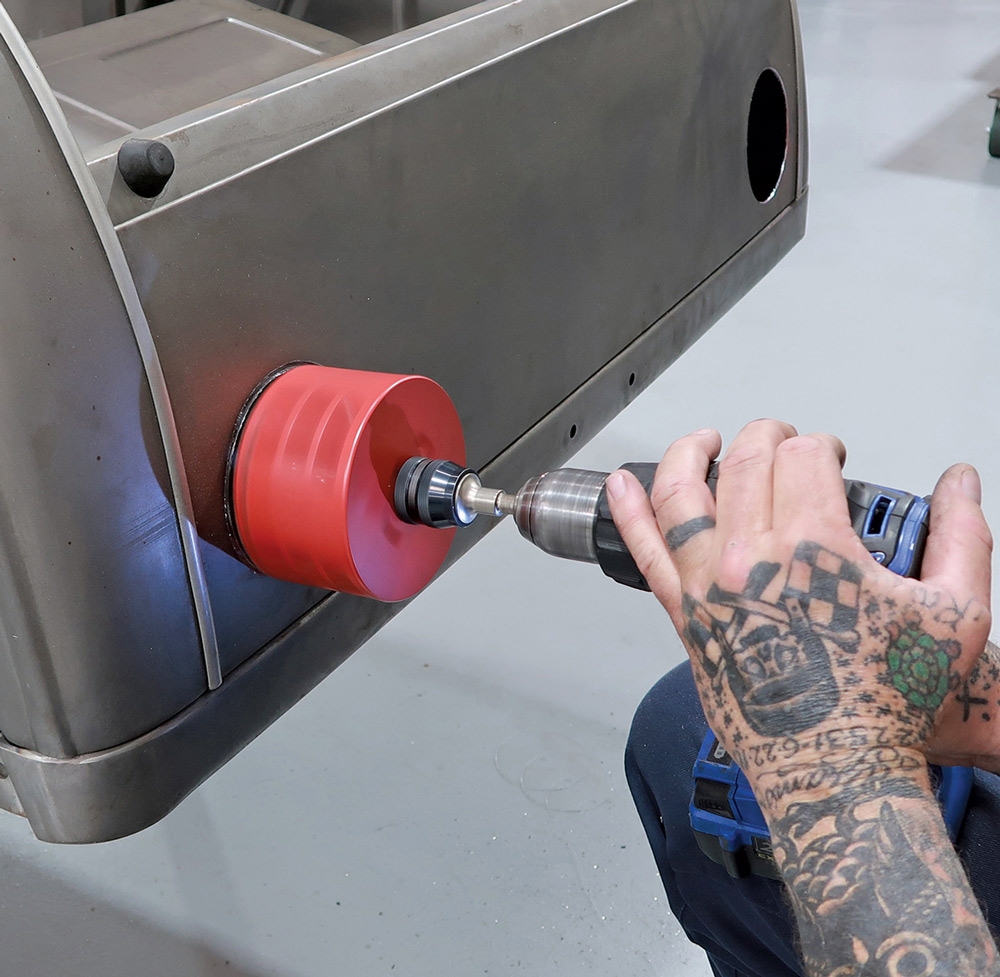 hand using hole saw to make opening for tail lights 