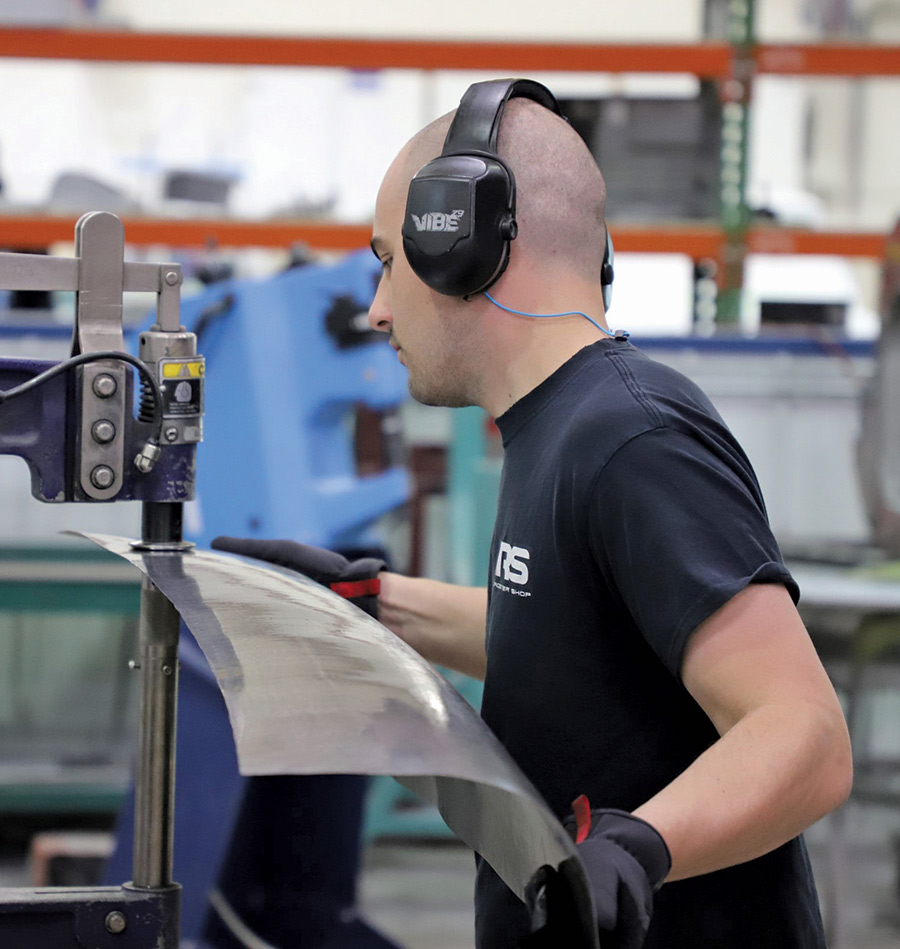 person using a Yoder power hammer to contour a steel sheet into the shape of the roof panel