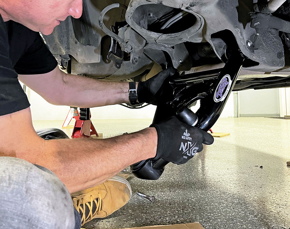 person sitting on ground wearing gloves while adding new control arms 