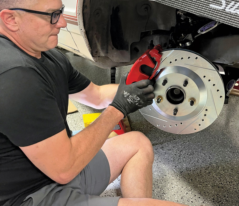 man sitting on ground installing twin-piston calipers onto hub 