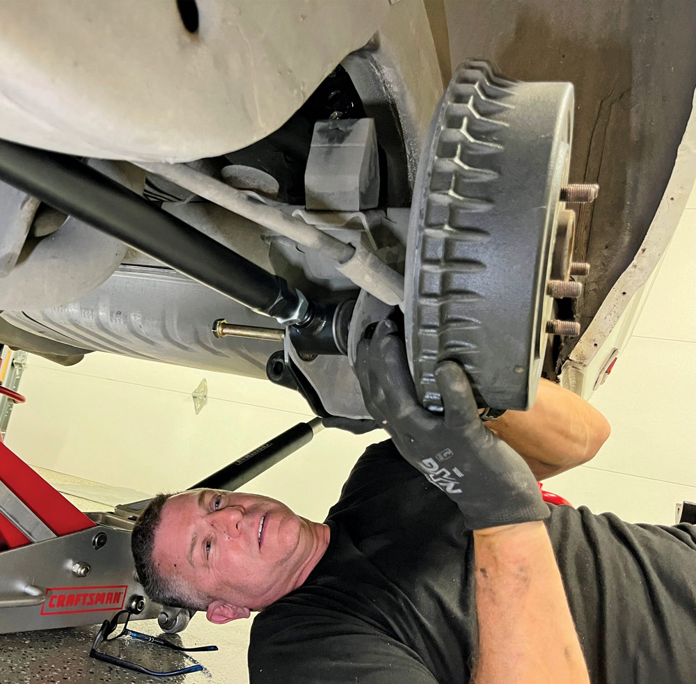man laying on ground to install Detroit Speed’s Swivel Link rear suspension kit