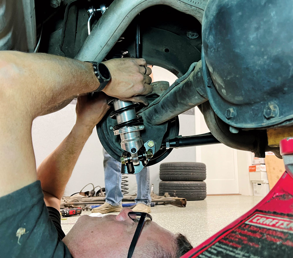 person bolting coilovers into place
