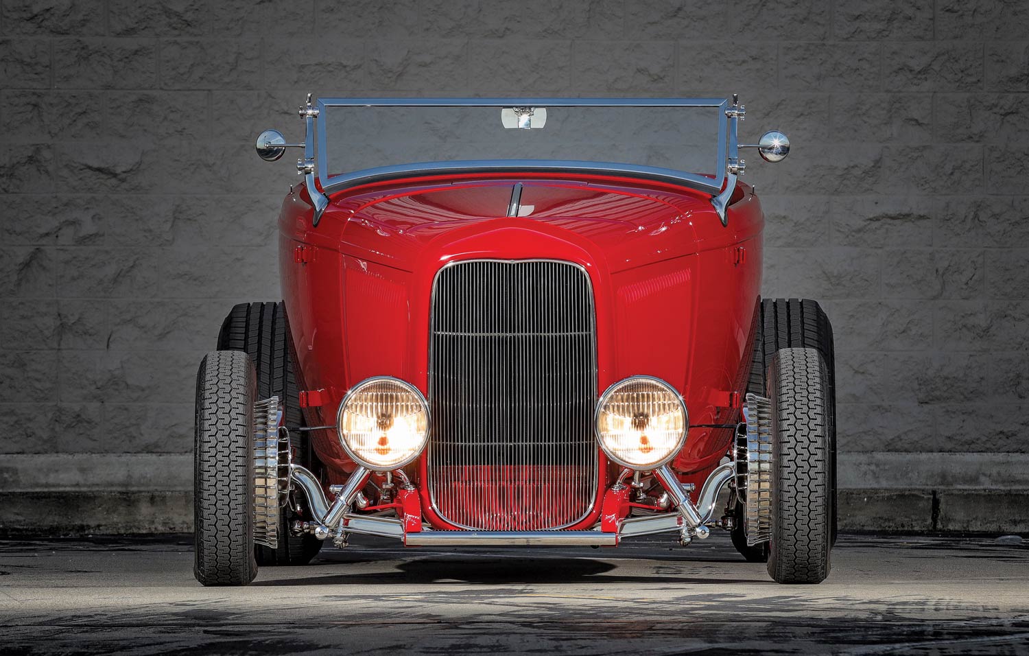 Front view of a 1932 Ford Roadster with bright headlights and a chrome grille