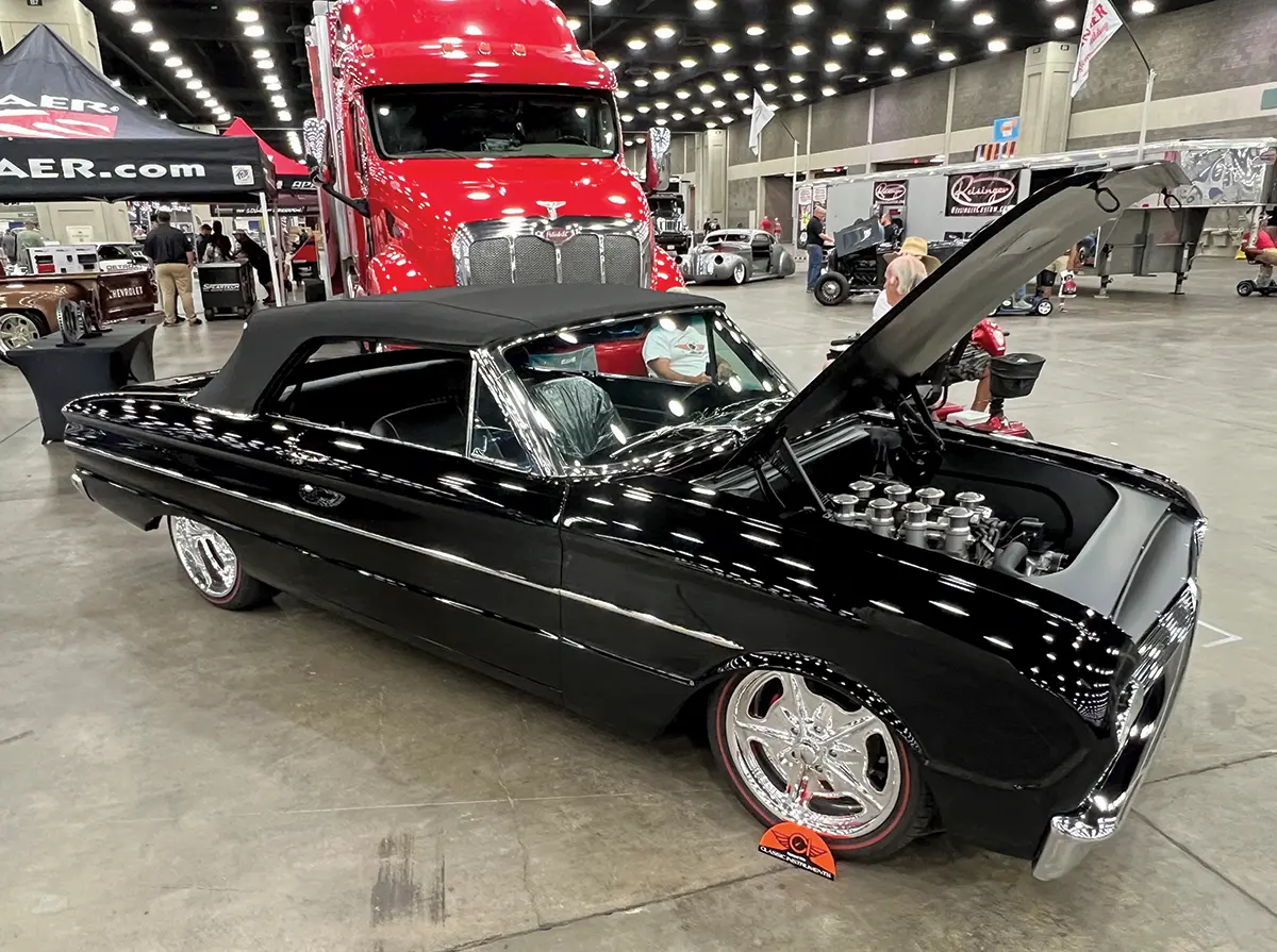 A black 1964 Ford Galaxie Convertible on display, highlighting its pristine engine bay at the event