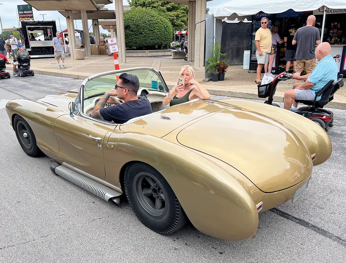 A unique gold-bodied roadster cruising past spectators at the 2024 Street Rod Nationals event
