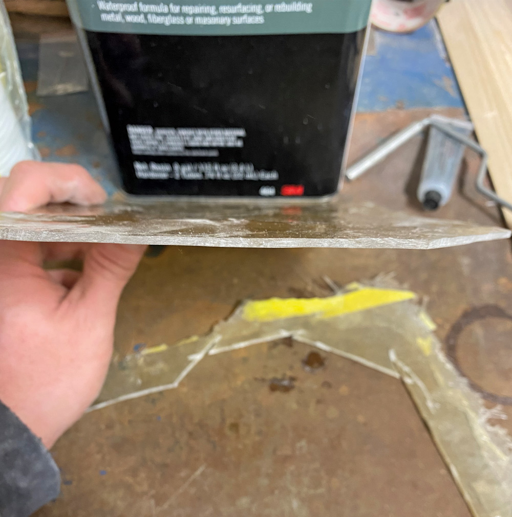 hand holding up fiberglass showing the thickness of the corvette's firewall 