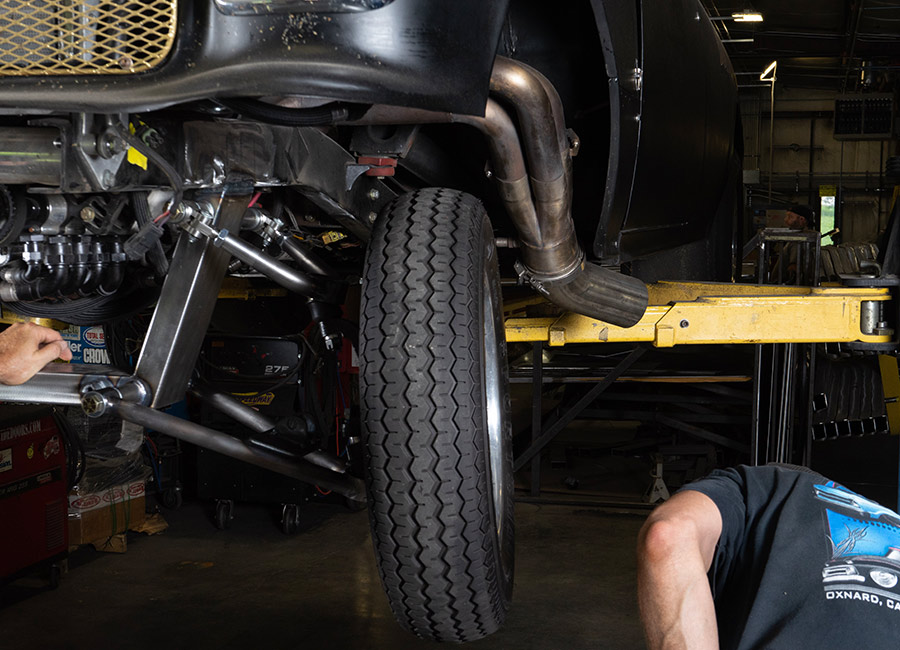 Mechanic working on the 1955 Chevrolet Bel Air gasser, adjusting the front suspension components during installation