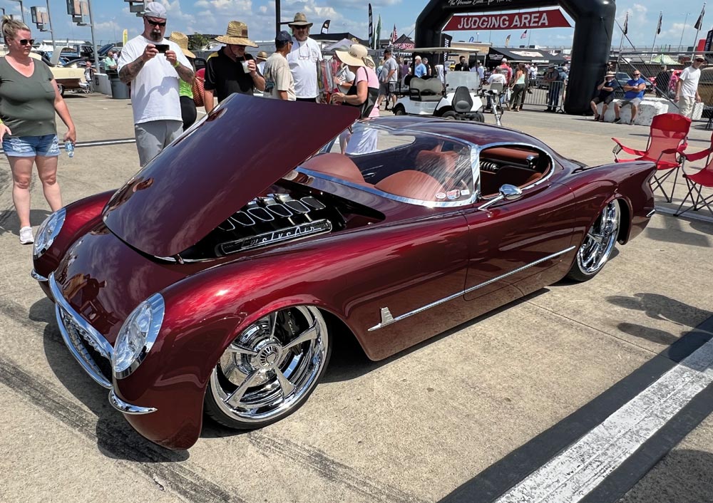 red car with hood lifted at a car show