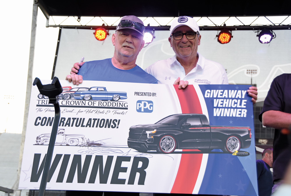 winner at a car show holding a sign on stage