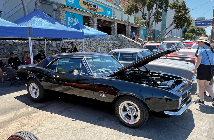 A black 1967 Chevrolet Camaro SS with hood open displayed at a car show