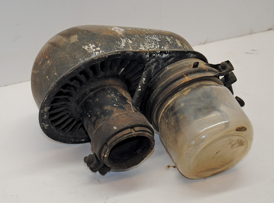 A dusty vintage air filter assembly, likely from an old vehicle, showing signs of age and wear