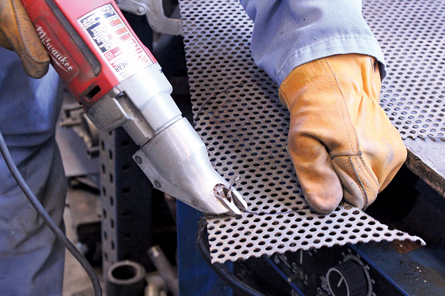 Perforated metal being cut with power shears during a restoration project
