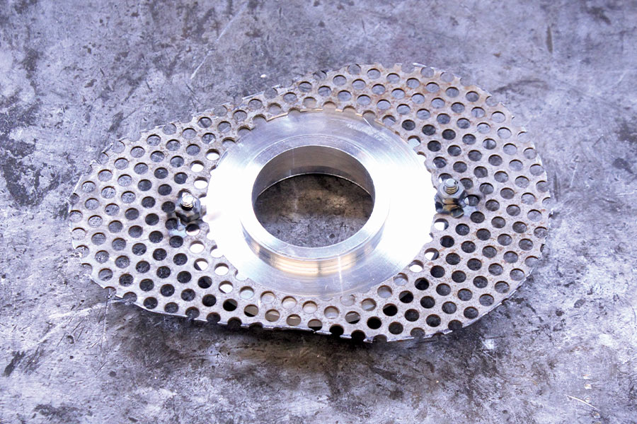 Completed custom perforated metal part with a machined center piece