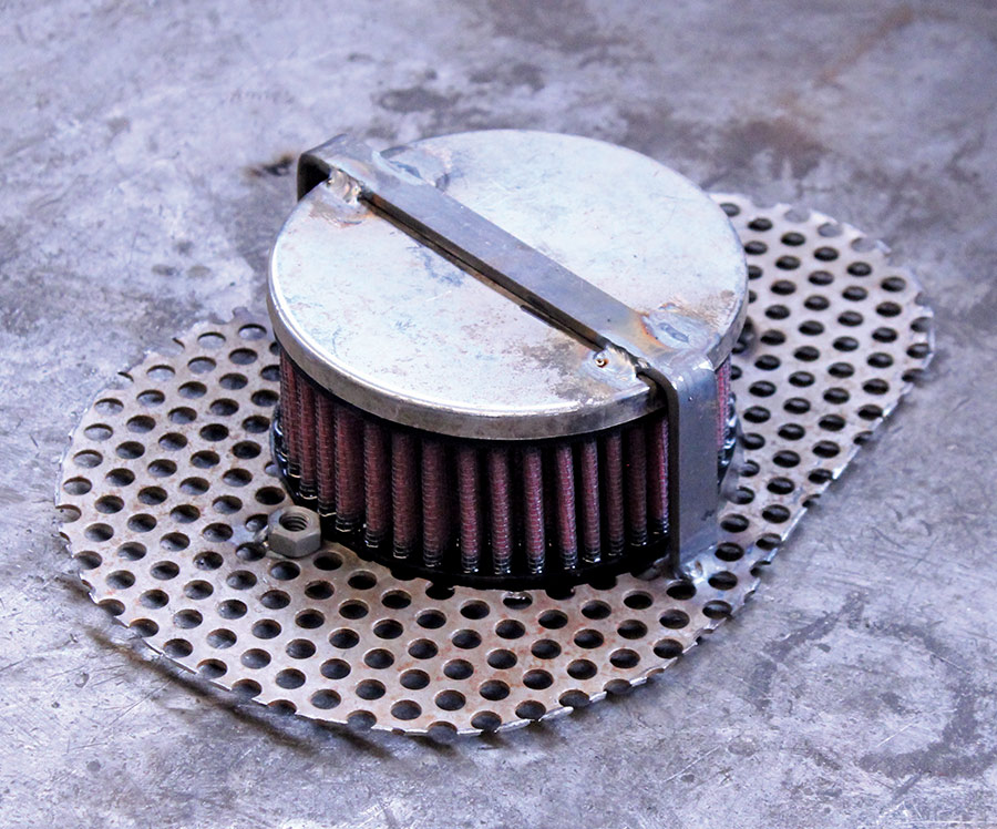 The same air filter cover, now with the filter element installed, on a workshop table
