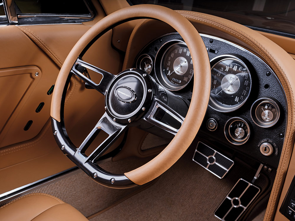 Close-up of the 1966 Chevrolet Corvette Stingray’s steering wheel and instrument cluster, featuring vintage dials