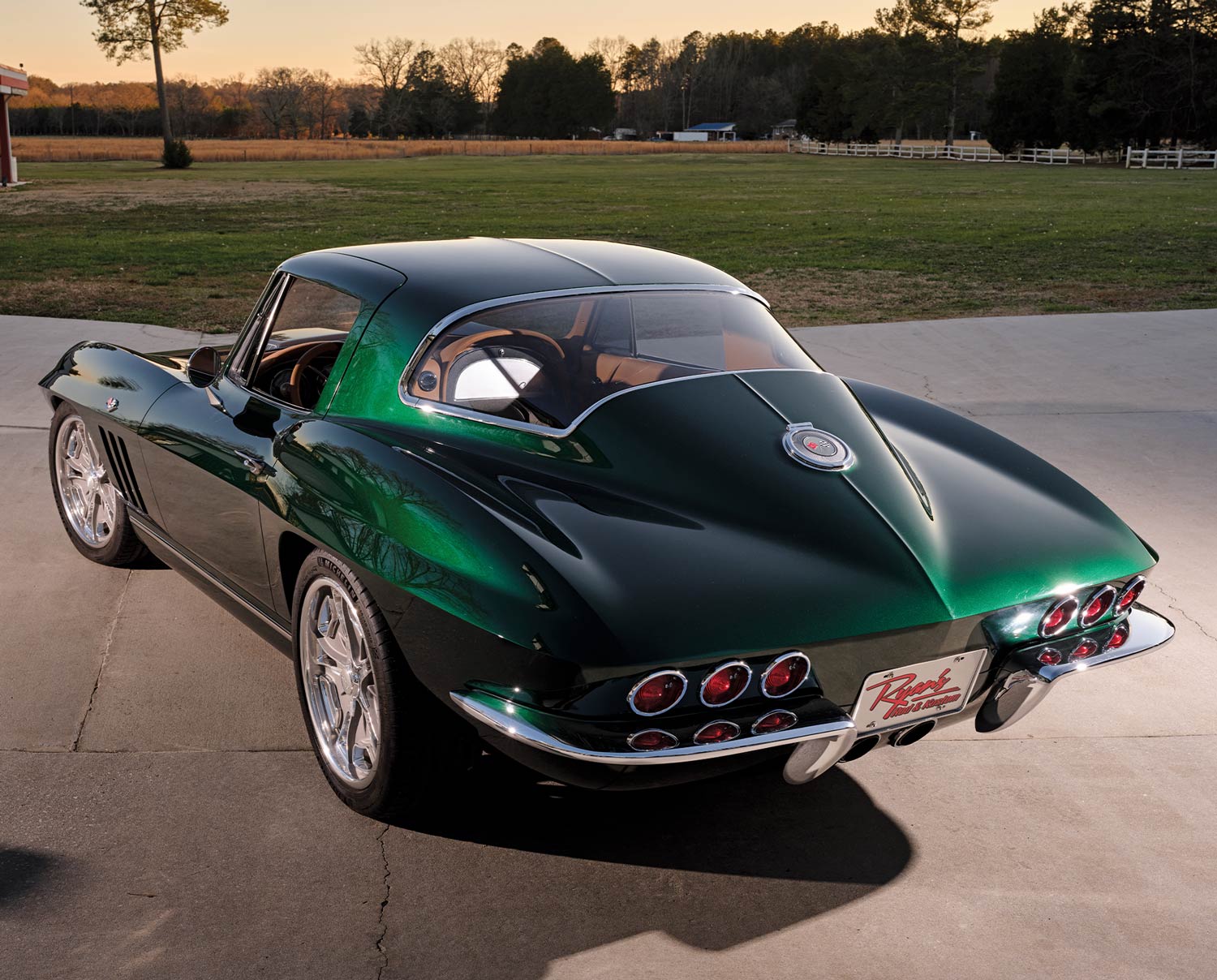 Angled rear shot of a 1966 Chevrolet Corvette Stingray, showcasing its sleek body lines under the evening light