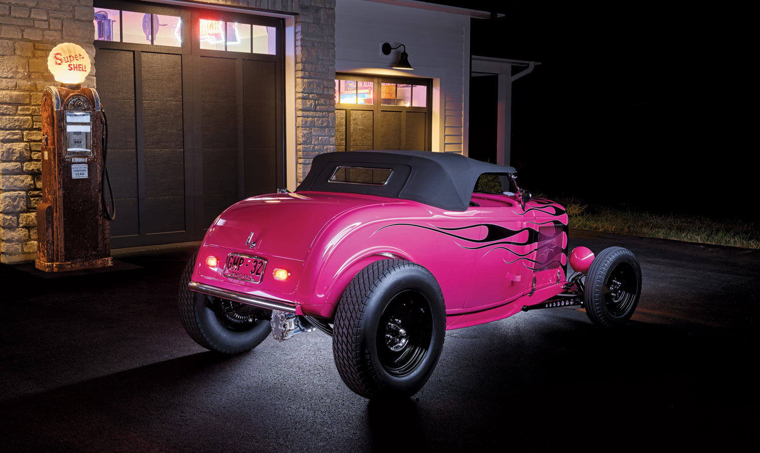 A 1932 Ford Roadster driving on an open road, piloted by a driver in retro attire