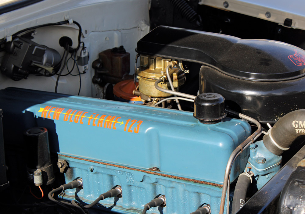 A blue engine block labeled "New Blue Flame" in orange lettering in a white vehicle's engine compartment.