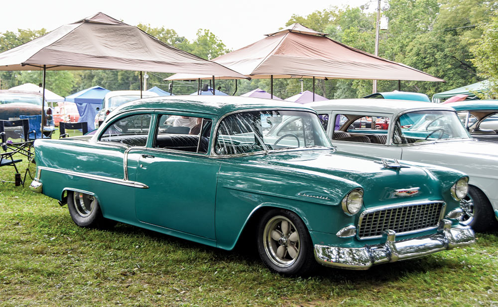 a blue-green 1955 Chevy 210 parked in shade at the Tri-Five Nationals