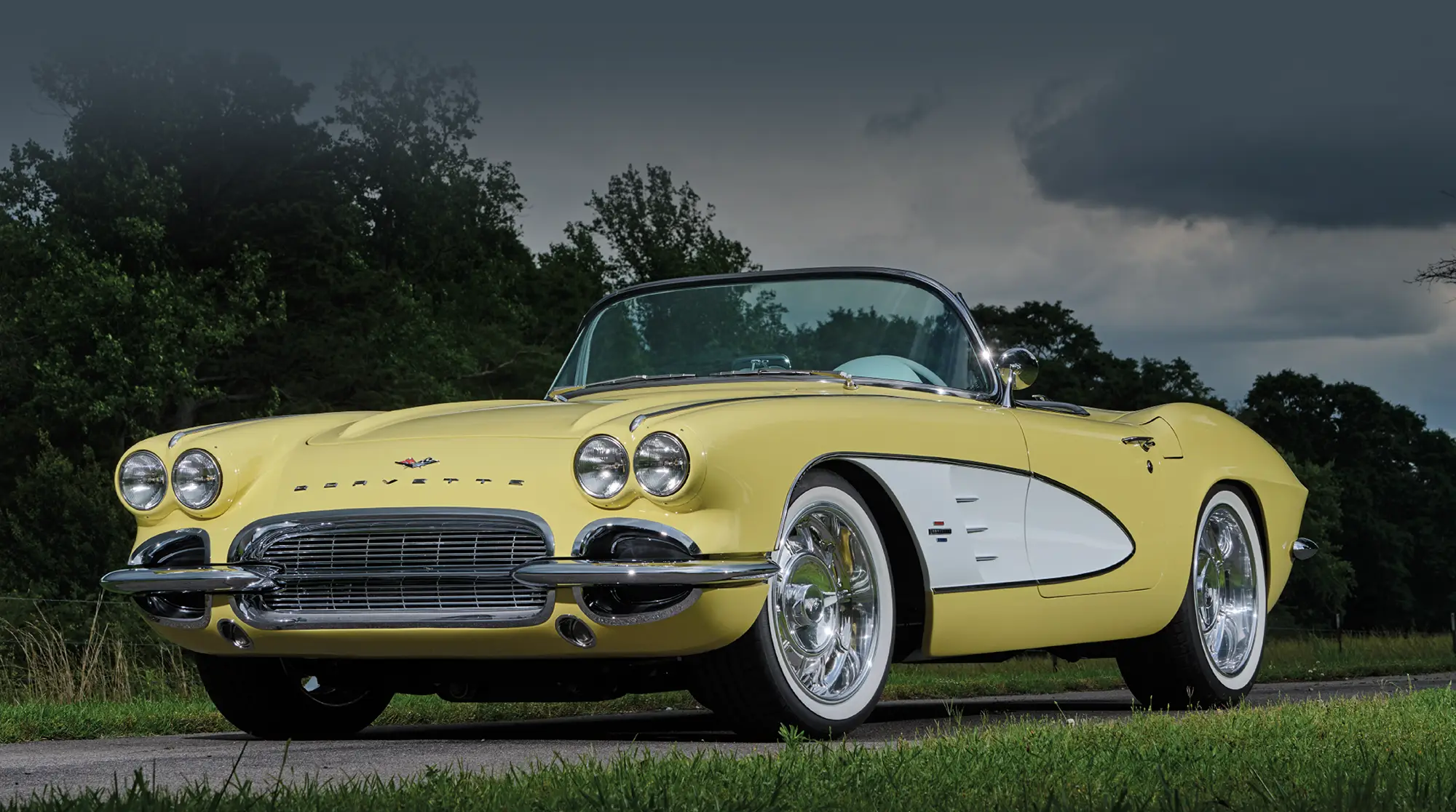 1961 Corvette convertible yellow parked country road lush greenery background