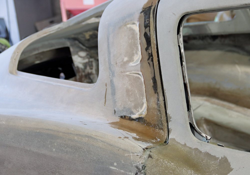 Close-up of C2 Corvette's B-pillar repair with detailed fiberglass reinforcement and shaping work