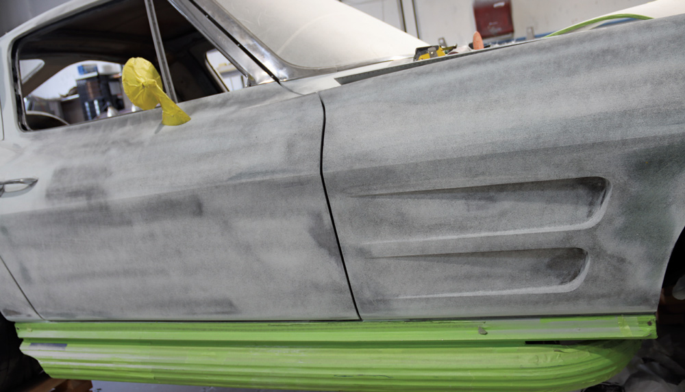 C2 Corvette side panel showing pre-paint prep with taped-off rocker panels and sanded fiberglass bodywork