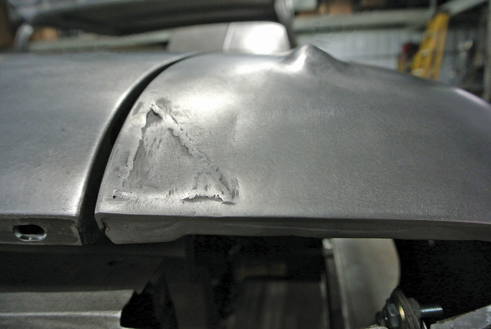 initial metalwork repair on a 1959 Impala fender, showing dents and stripped surface for welding