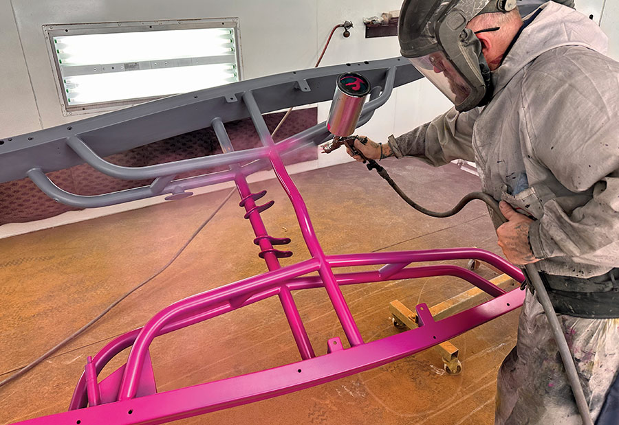 Bright pink finish being applied to the tubular frame, emphasizing its bold custom design