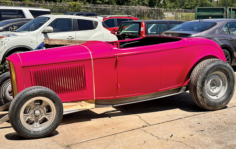 Fully assembled 1932 Ford roadster with a vibrant pink finish parked outside the workshop