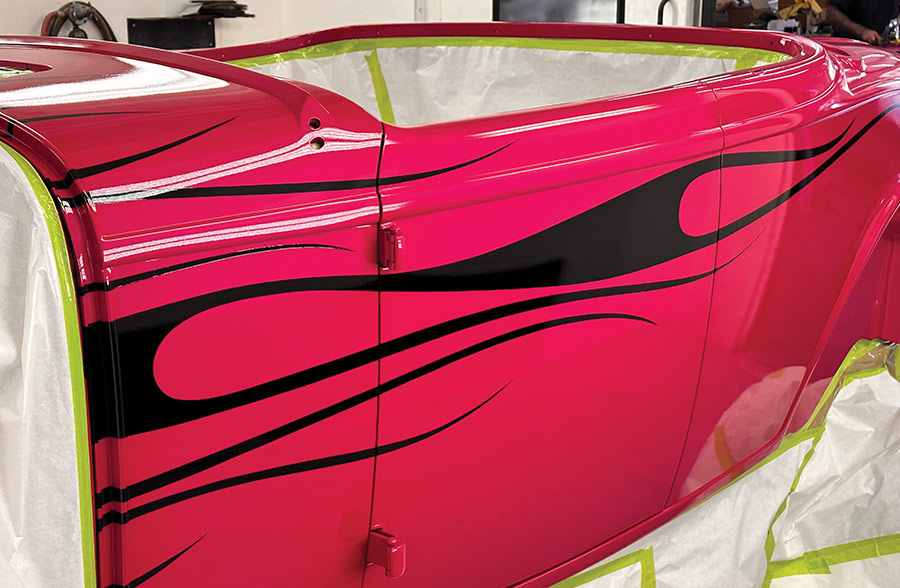 Side panel of the roadster showcasing a glossy black flame design over a vibrant pink base