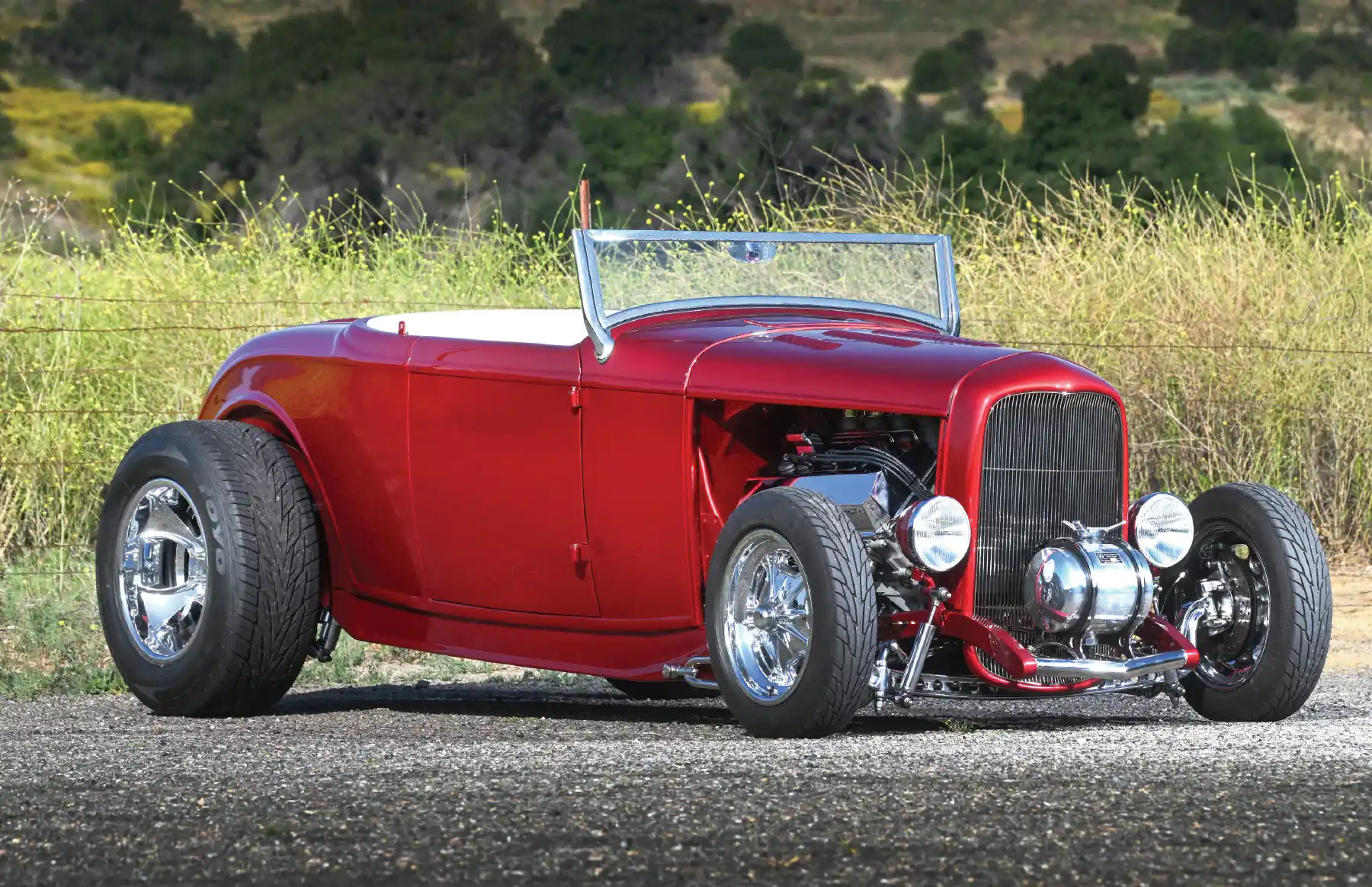1932 Ford Roadster side profile showcasing sleek candy red finish and deep-dish chrome wheels