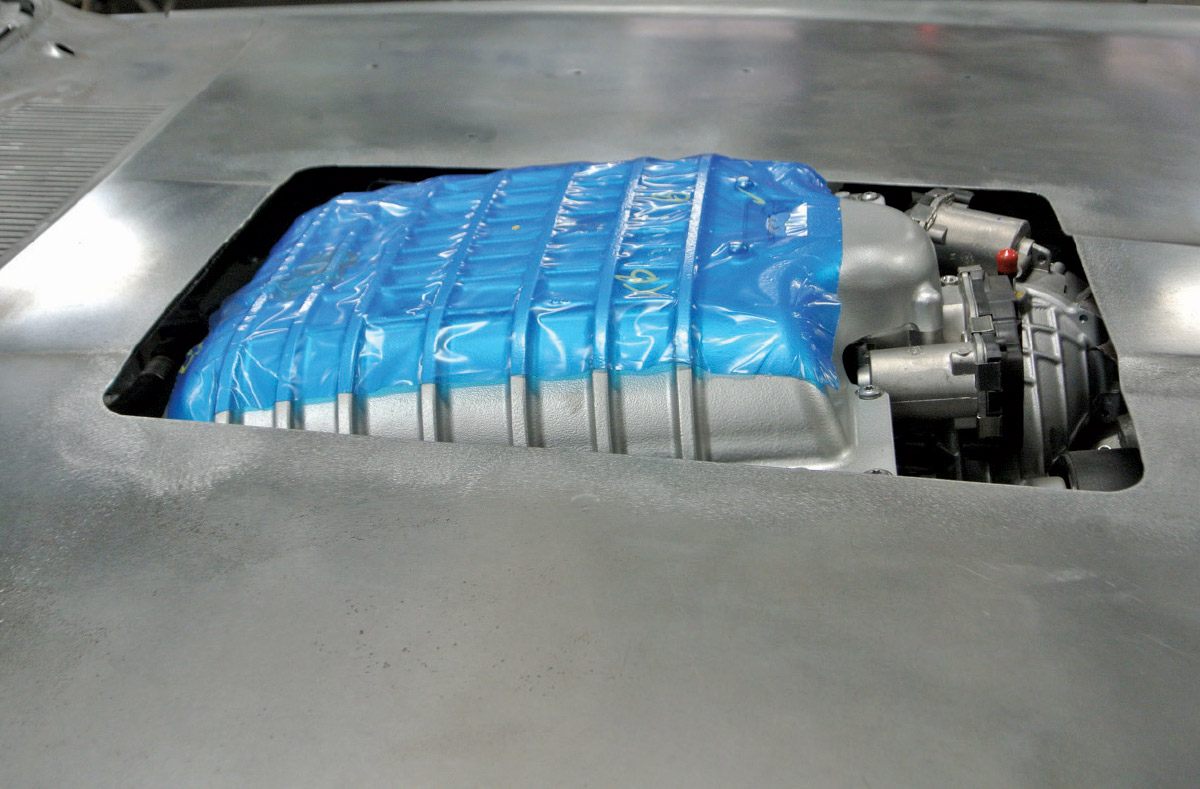 Custom hood showing supercharger intake wrapped in protective blue film during fitting