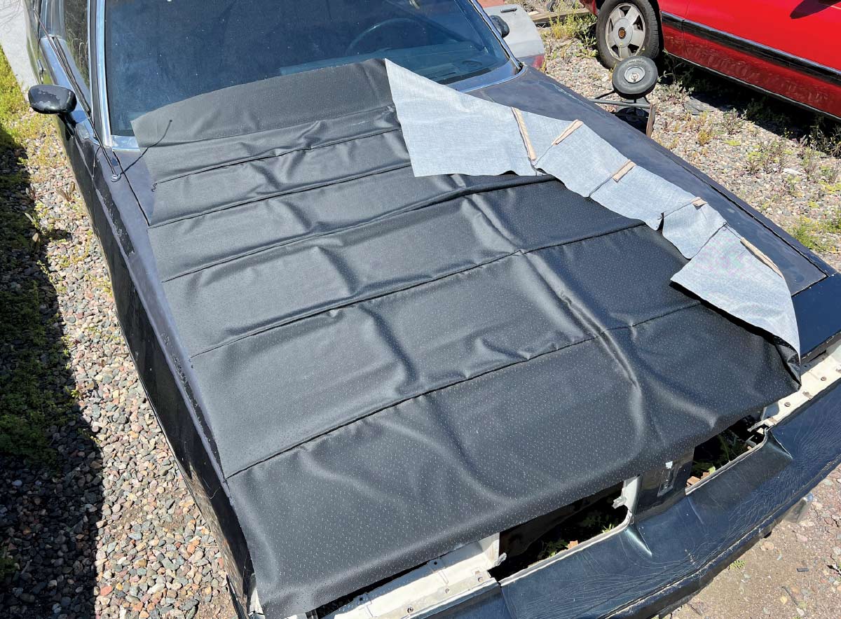 New black headliner fabric laid out on the roof of a 1970 Chevy Nova