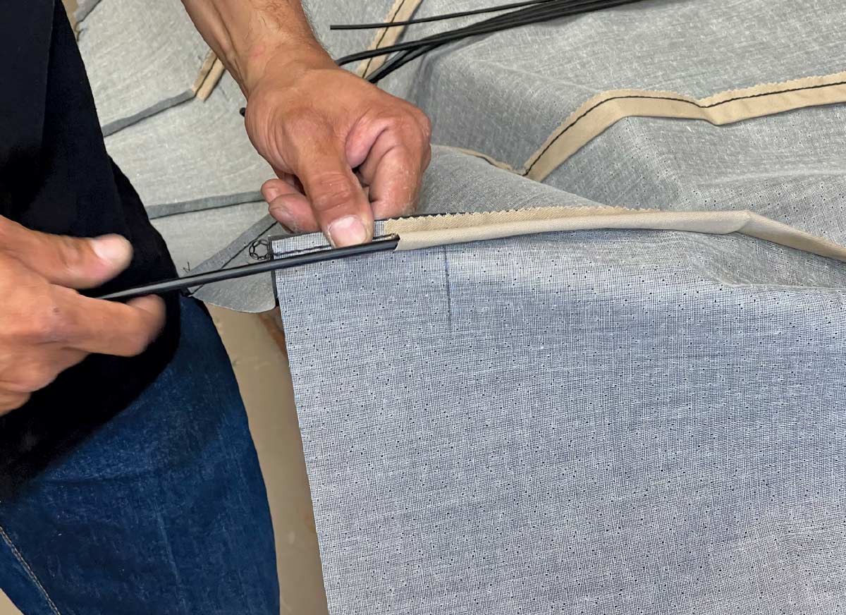 Worker inserting support rods into the headliner fabric for a 1970 Chevy Nova