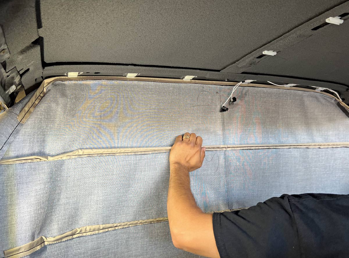 Final adjustments and smoothing of the headliner fabric in a 1970 Chevy Nova