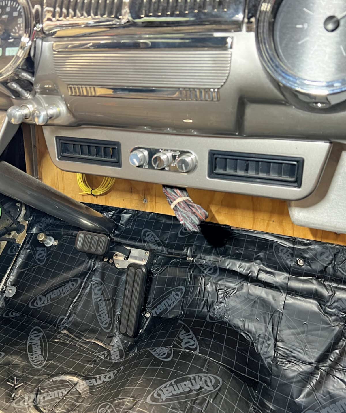 Under-dash Vintage Air AC vents installed in a classic car interior with chrome dash trim and a black Dynamat-lined floor