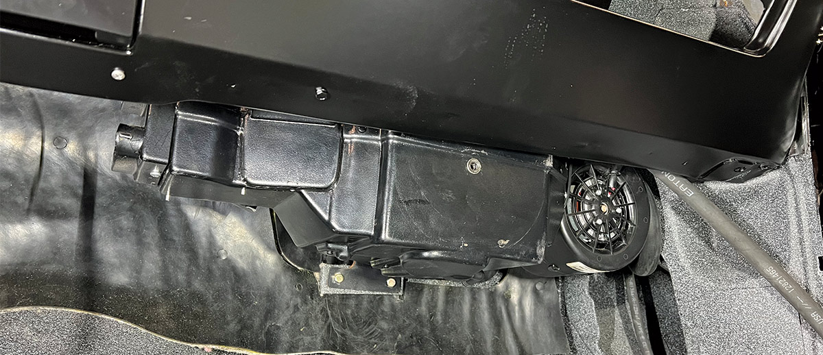 Mounted Vintage Air evaporator unit under the dashboard of a classic car, secured with black brackets