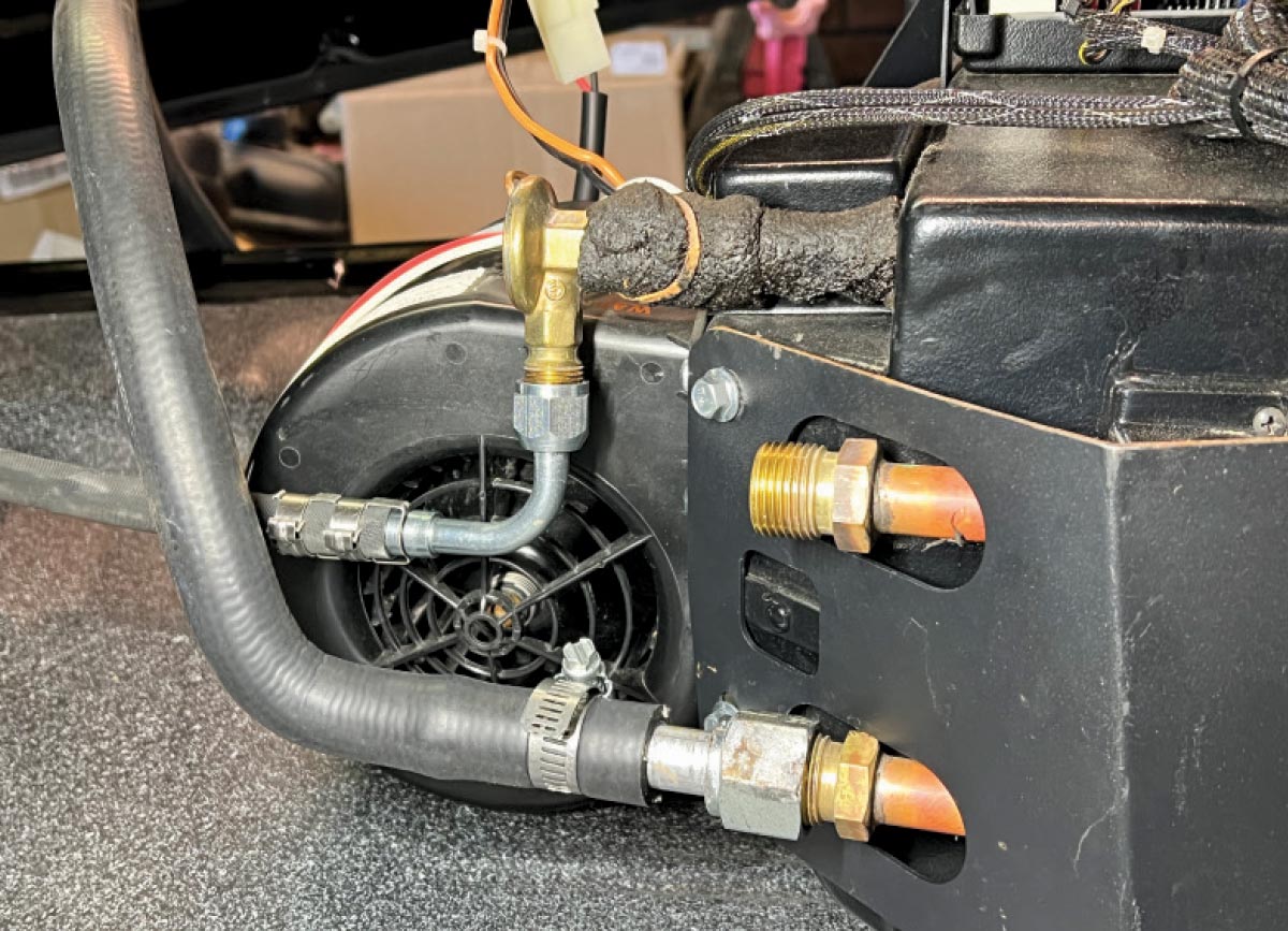 Close-up of Vintage Air evaporator fittings with refrigerant hoses, brass fittings, and electrical connectors