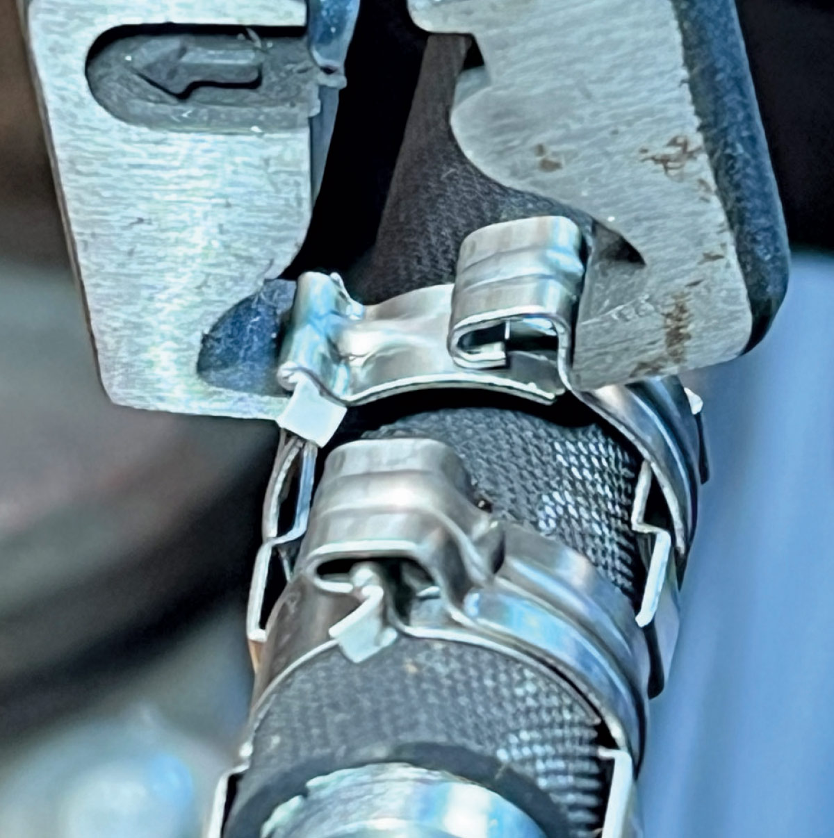 Crimping tool applying metal clamps to an AC hose fitting for a tight seal