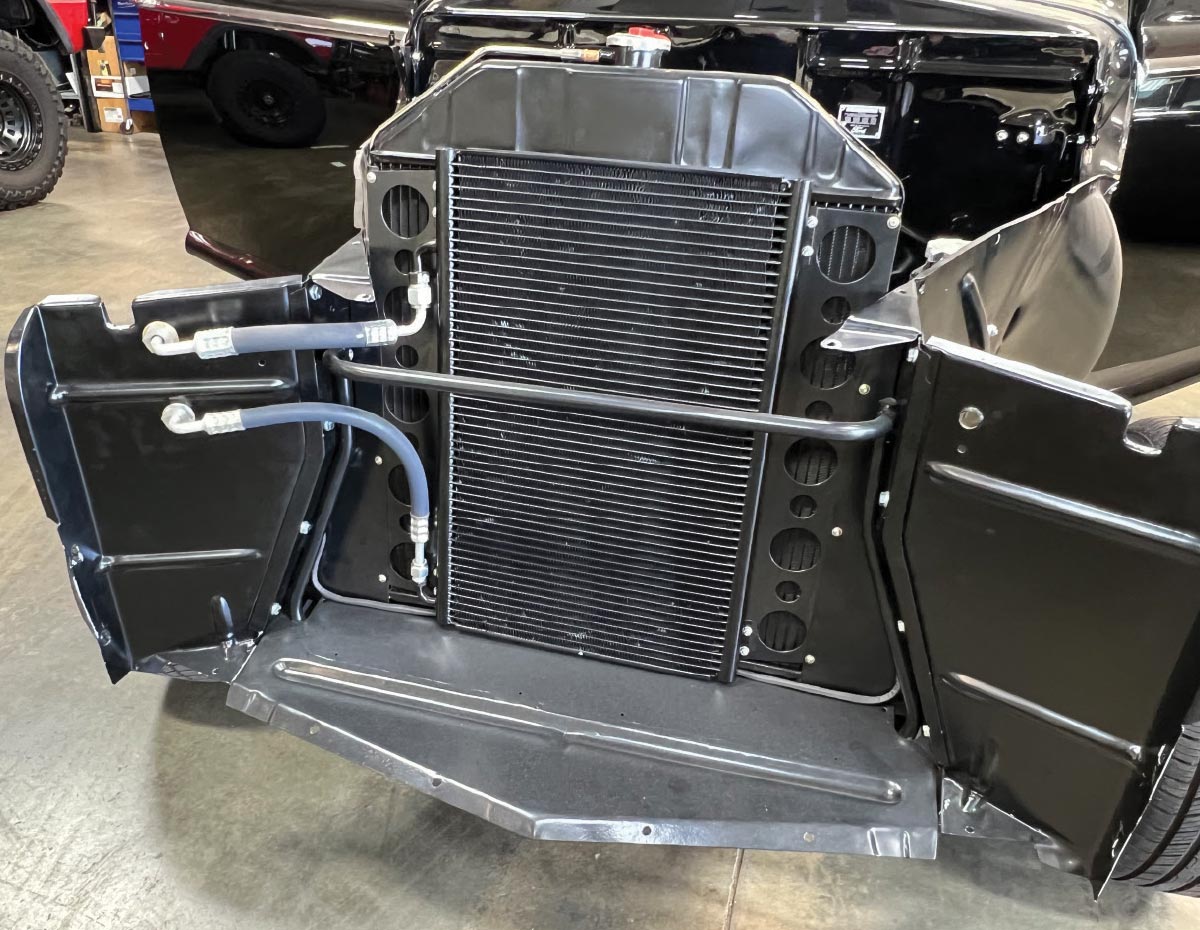 vintage car's front-end with a mounted AC condenser and routed refrigerant lines