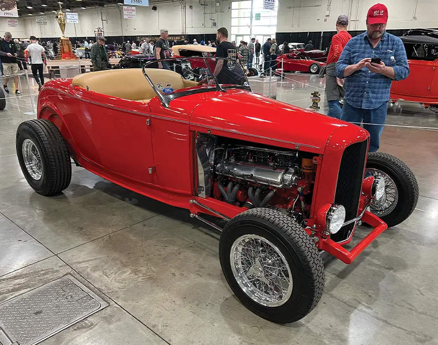 Bright red 1932 Ford roadster with a high-performance engine, wire wheels, and a tan interior