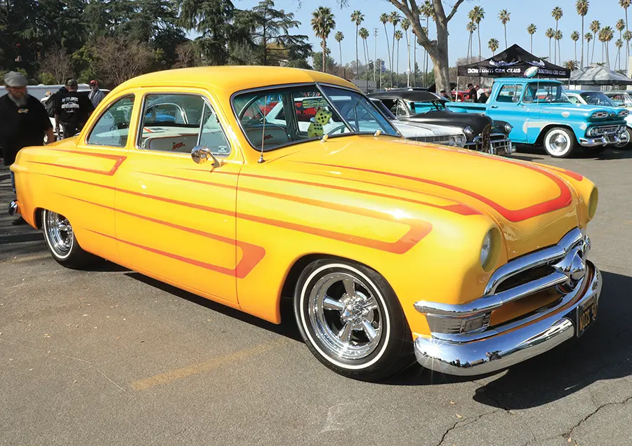 Yellow 1951 Ford coupe with orange scallop paint, chrome bumpers, and a classic custom stance