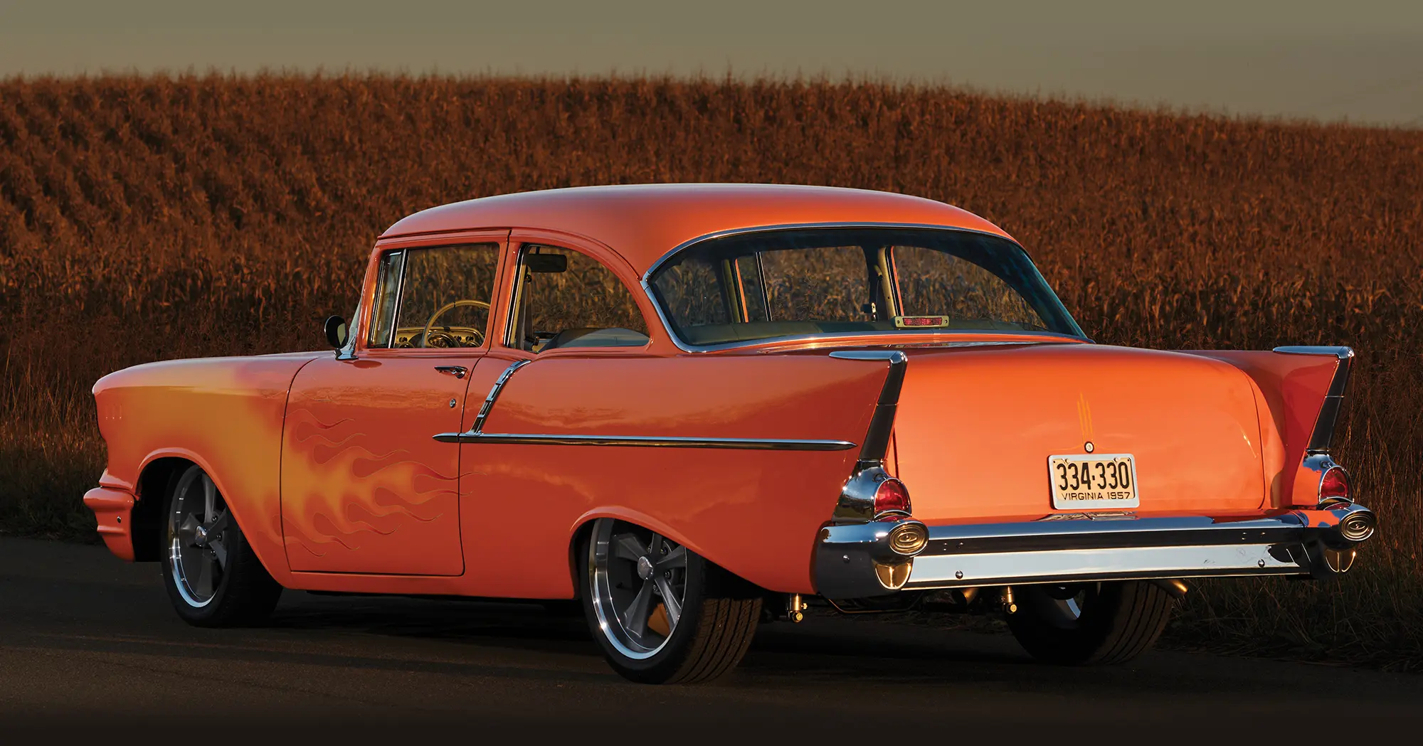 1957 Chevrolet Bel Air rear view showing its iconic tail fins and chrome bumper under golden evening light
