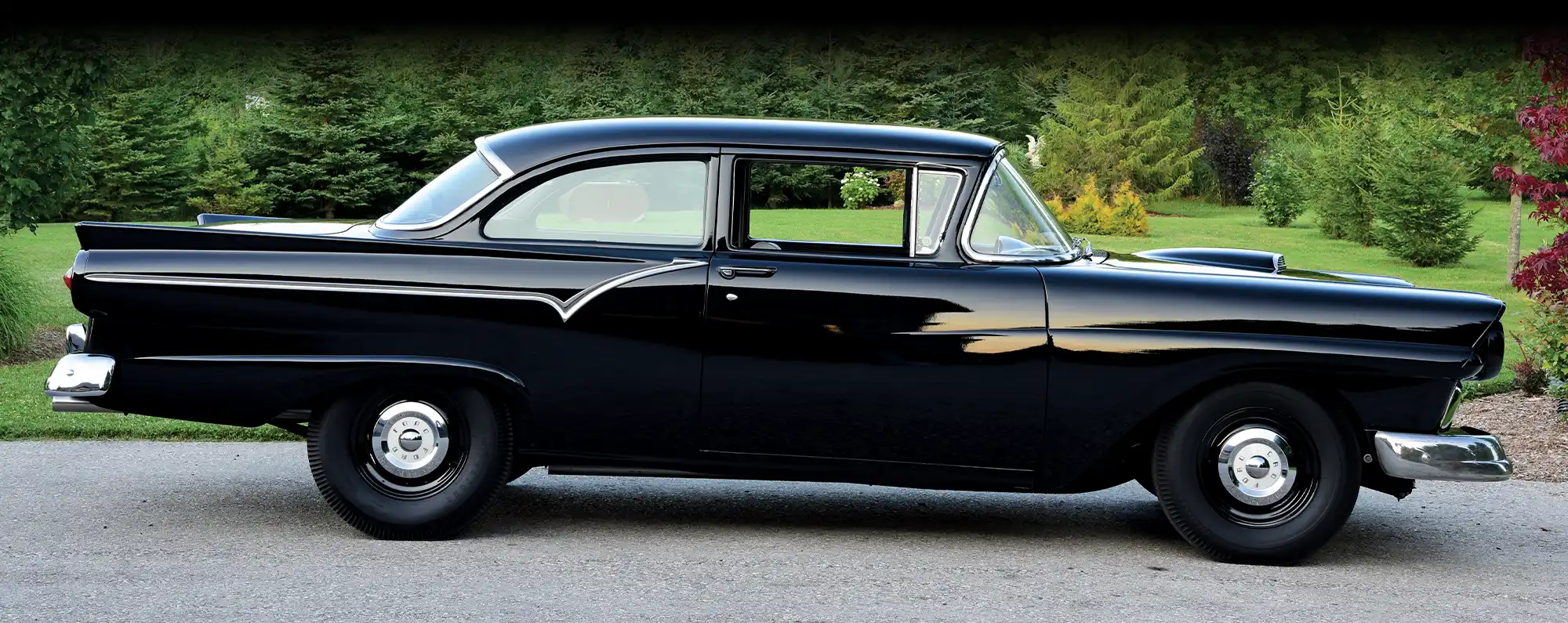 1957 Ford Custom Sedan with glossy black paint, chrome trim, and a sleek stance on steel wheels