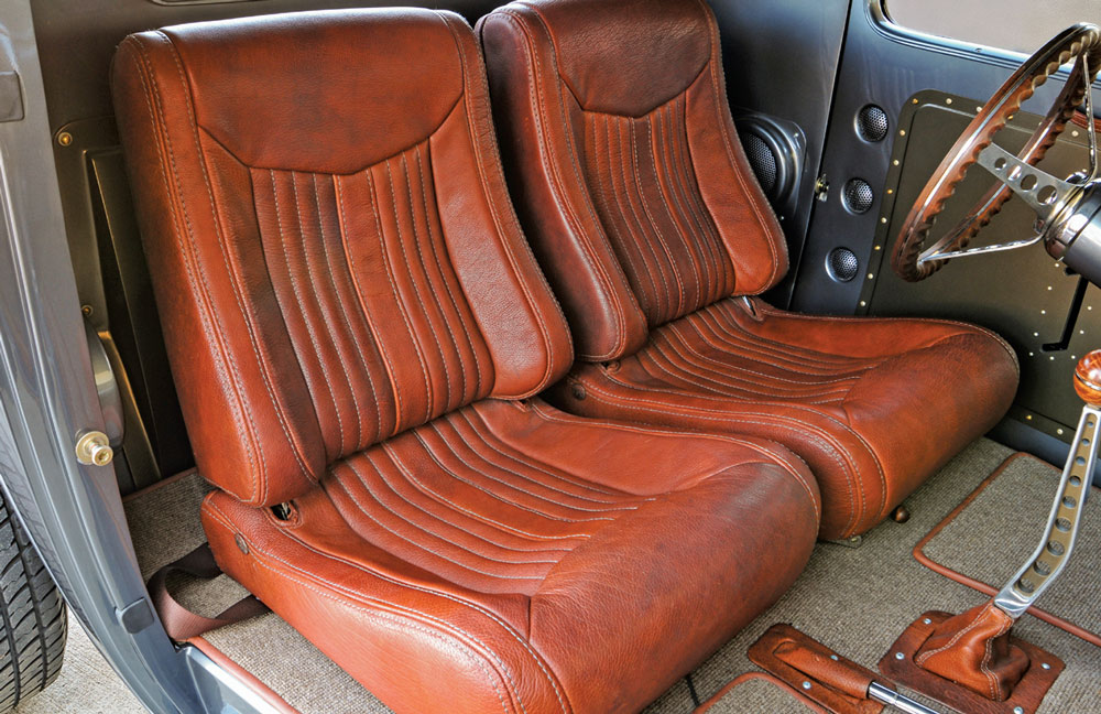 Vintage vehicle interior with brown leather bucket seats and a classic steering wheel.