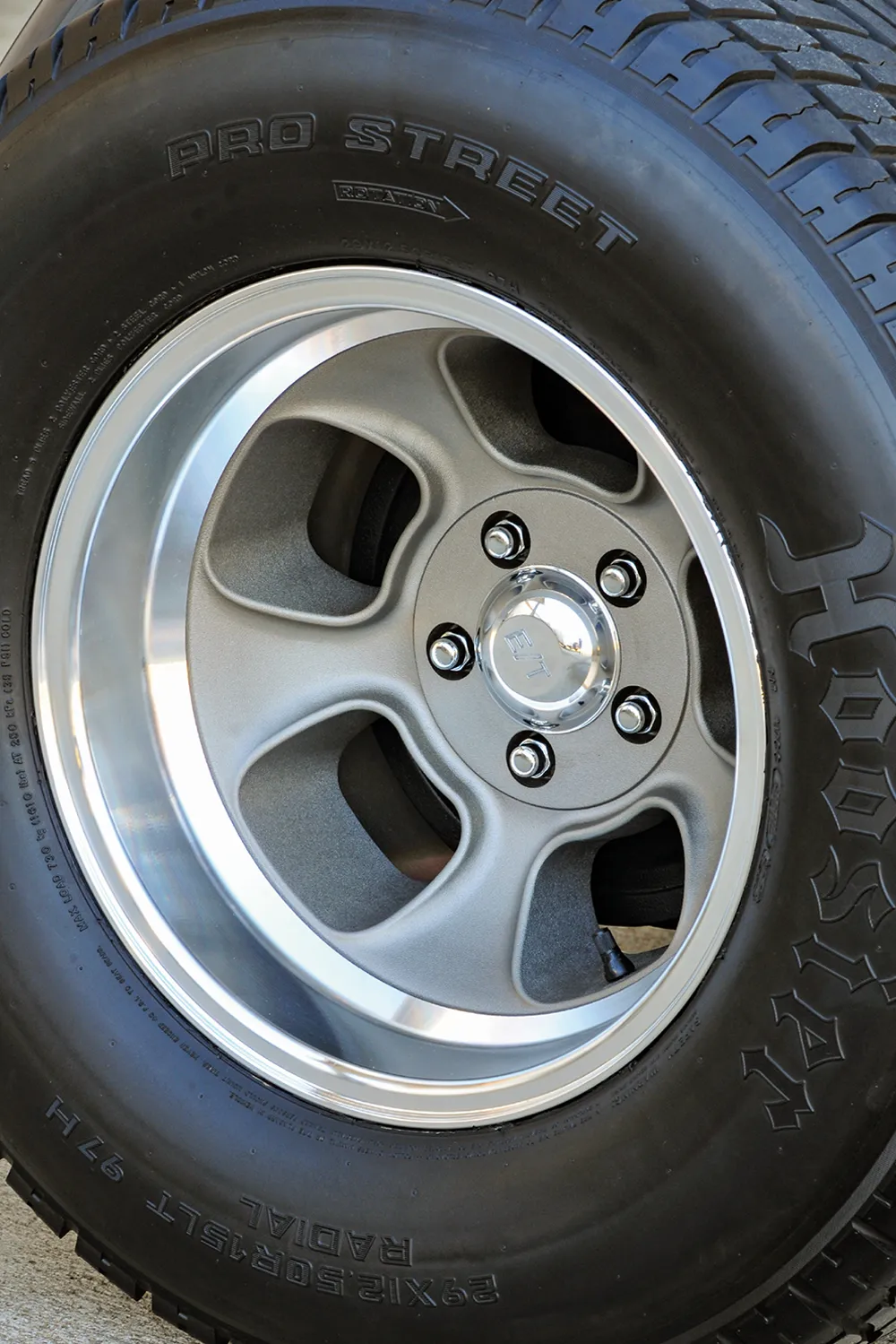 Close-up of a car wheel with a metallic rim and black tire featuring embossed text.